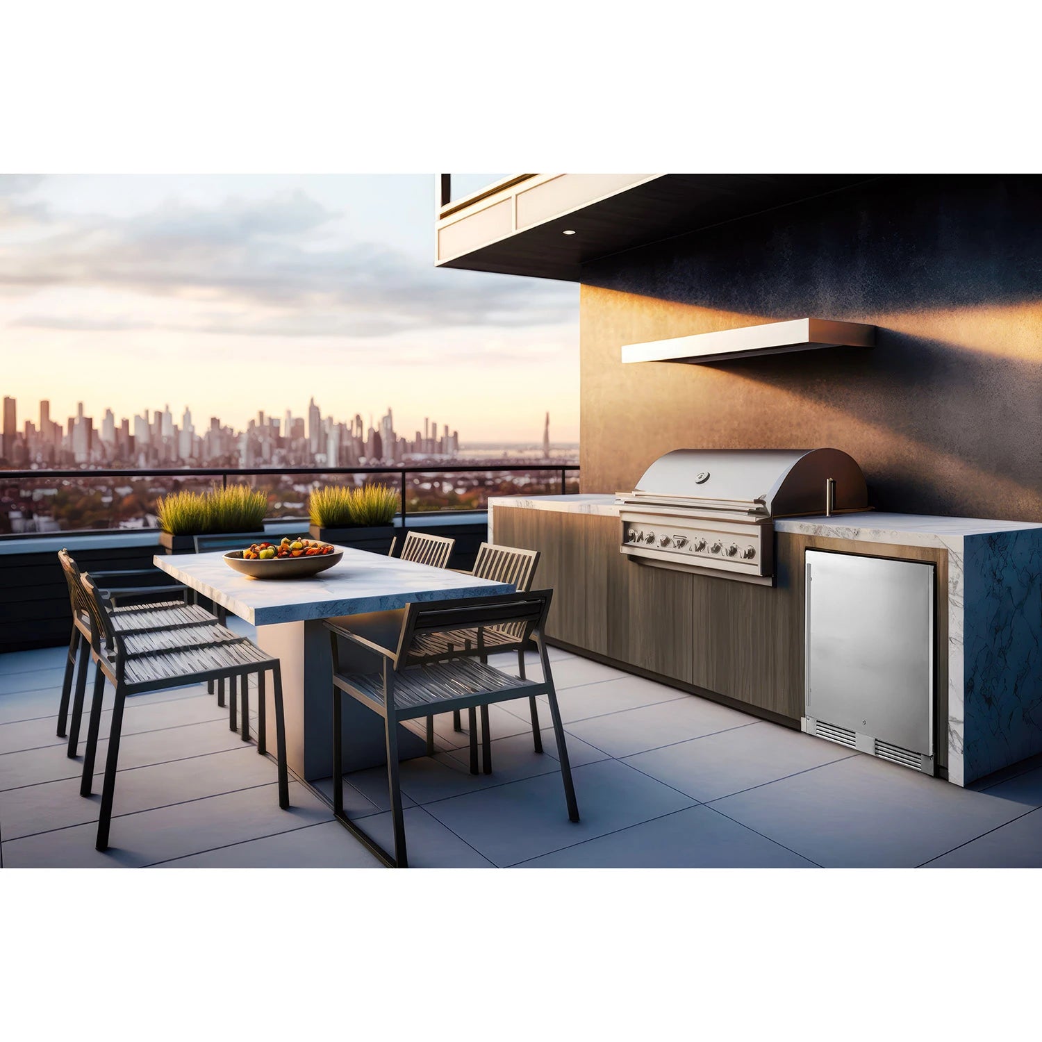 Moderne Außenküche auf einer Terrasse mit Stadtblick bei Sonnenuntergang, ausgestattet mit Esstisch, Edelstahlgrill und dem Unterbau-Outdoor-Kühlschrank Frigelux RETT136A.