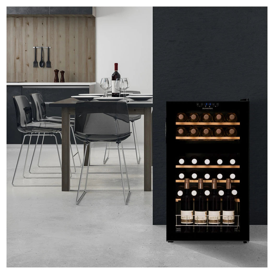 Dunavox Home-30 Weinkühlschrank in modernem Esszimmer mit Esstisch, beladener Doppelzone und Holzregalen