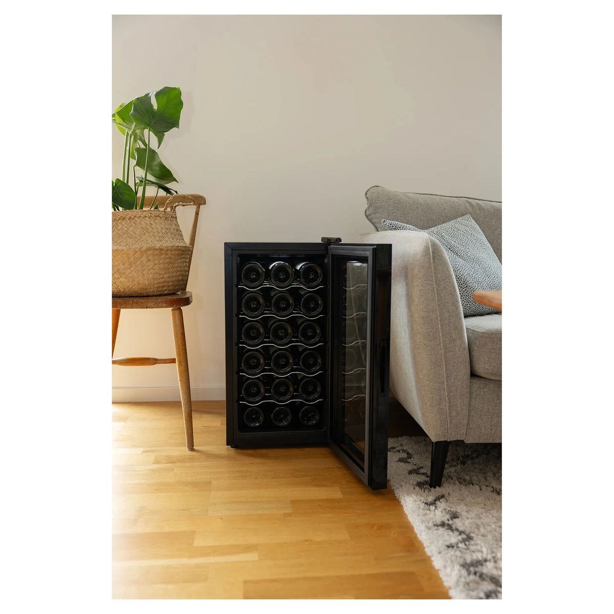 Freistehender Weinkühlschrank Cavin Tundra Collection 18 mit geöffneter Tür und gefülltem Innenraum neben einem Sofa im Wohnzimmer