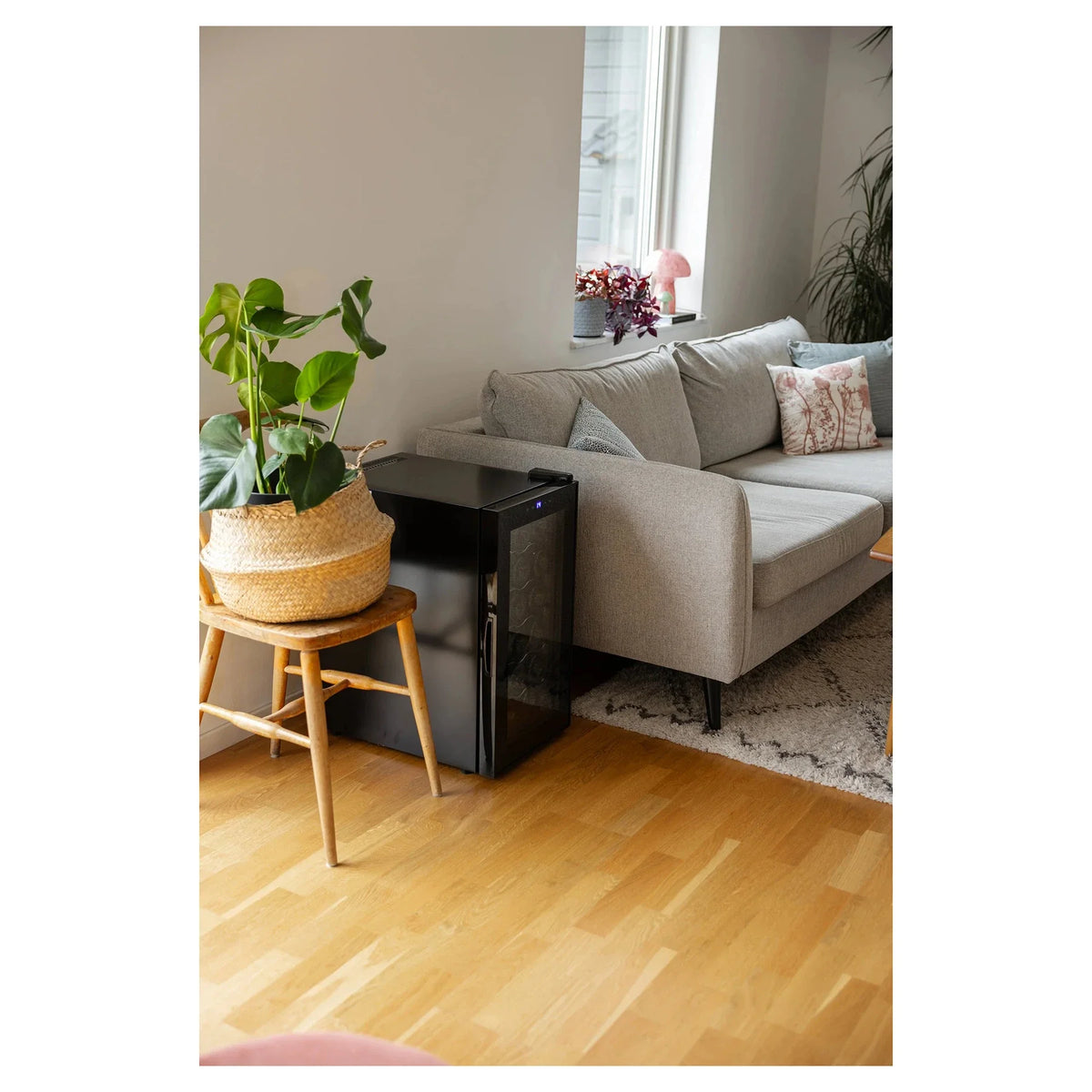 Freistehender Weinkühlschrank Cavin Tundra Collection 18 mit geschlossener Glastür neben einem Sofa im Wohnzimmer